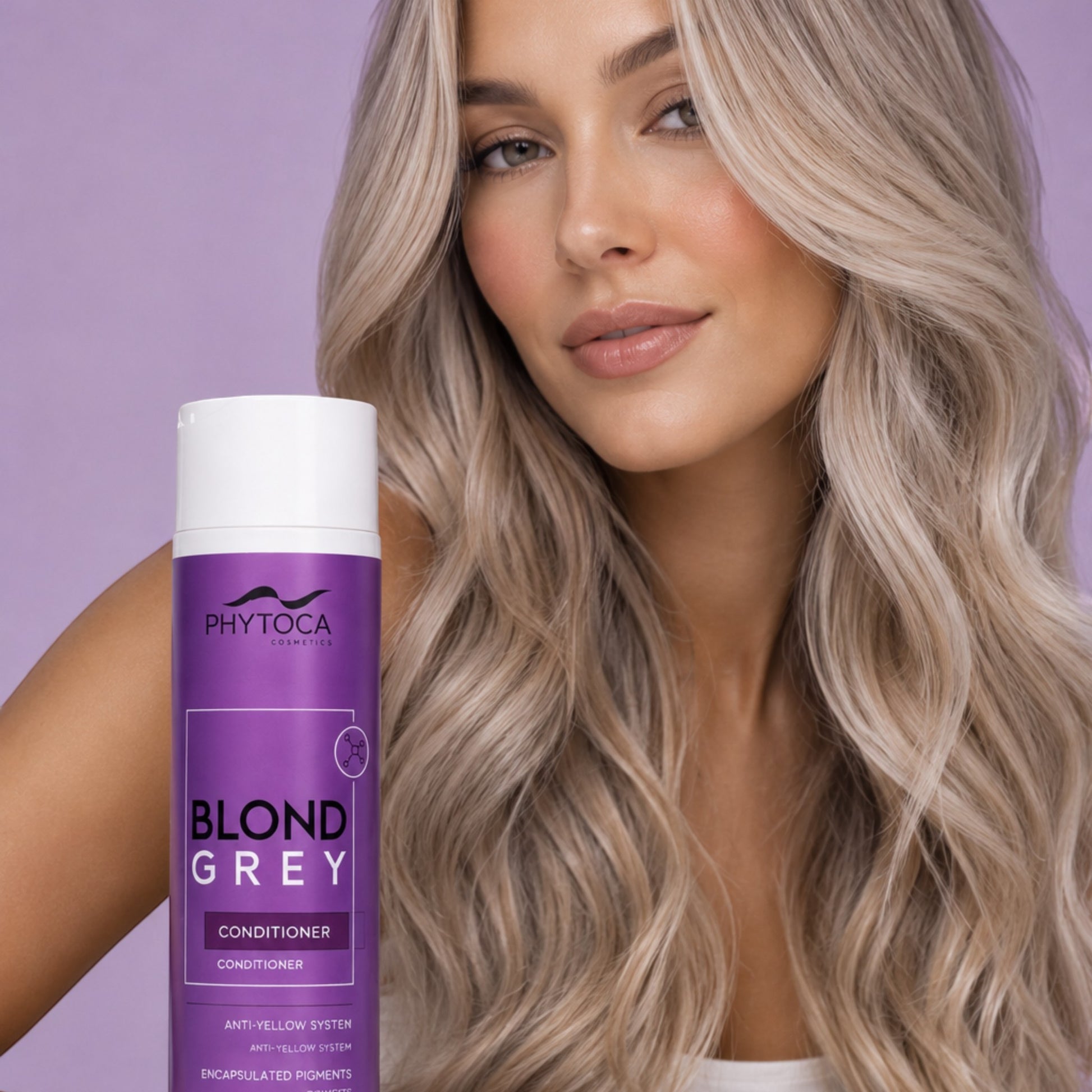 Mujer rubia con cabello platino posando junto al acondicionador Phytoca USA Blond Grey para eliminar tonos amarillos