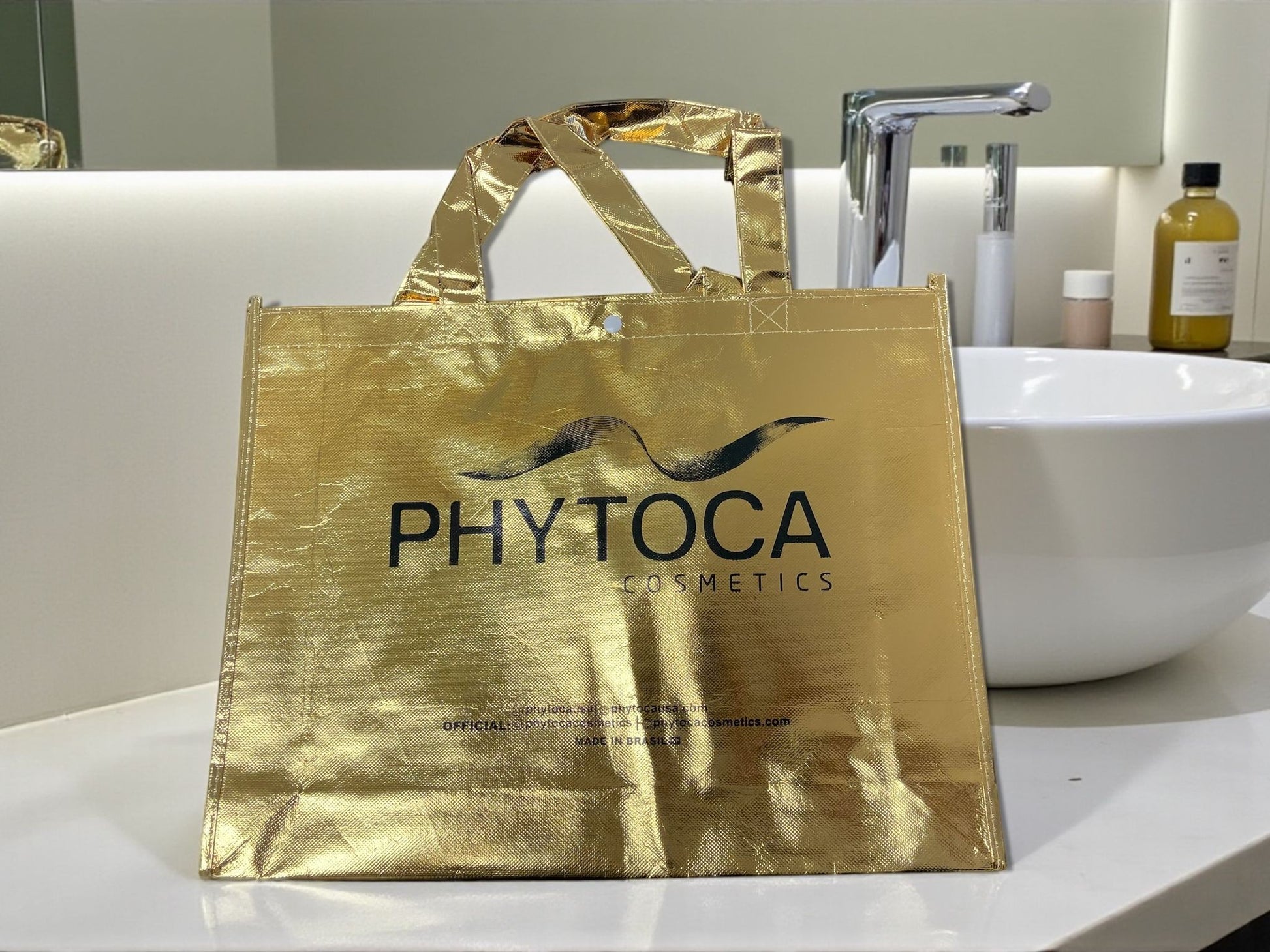 Bolsa de mano Phytoca USA de color dorado brillante con el logotipo de Phytoca Cosmetics impreso en negro.