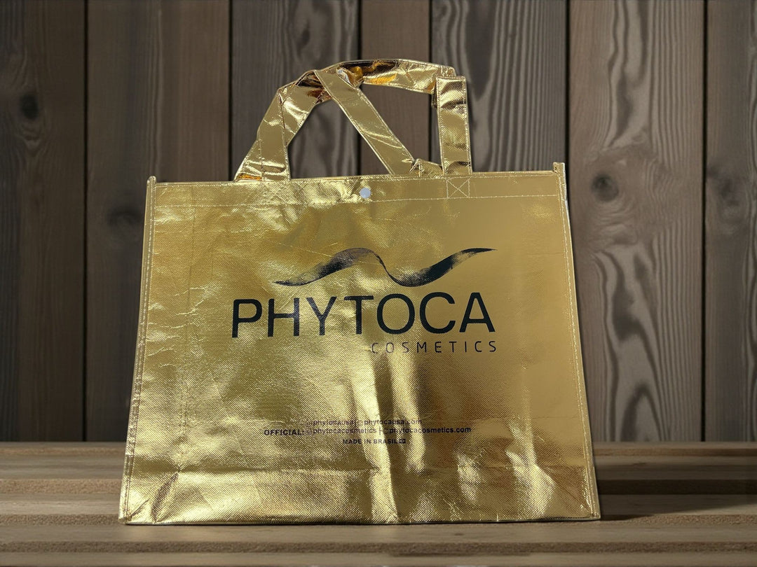 Bolsa de mano dorada Phytoca USA con acabado metálico y logo de Phytoca Cosmetics impreso en negro
