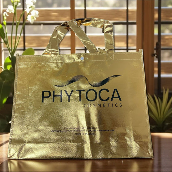 Bolsa de mano dorada Phytoca USA con acabado metálico y logotipo de la marca impreso en el centro