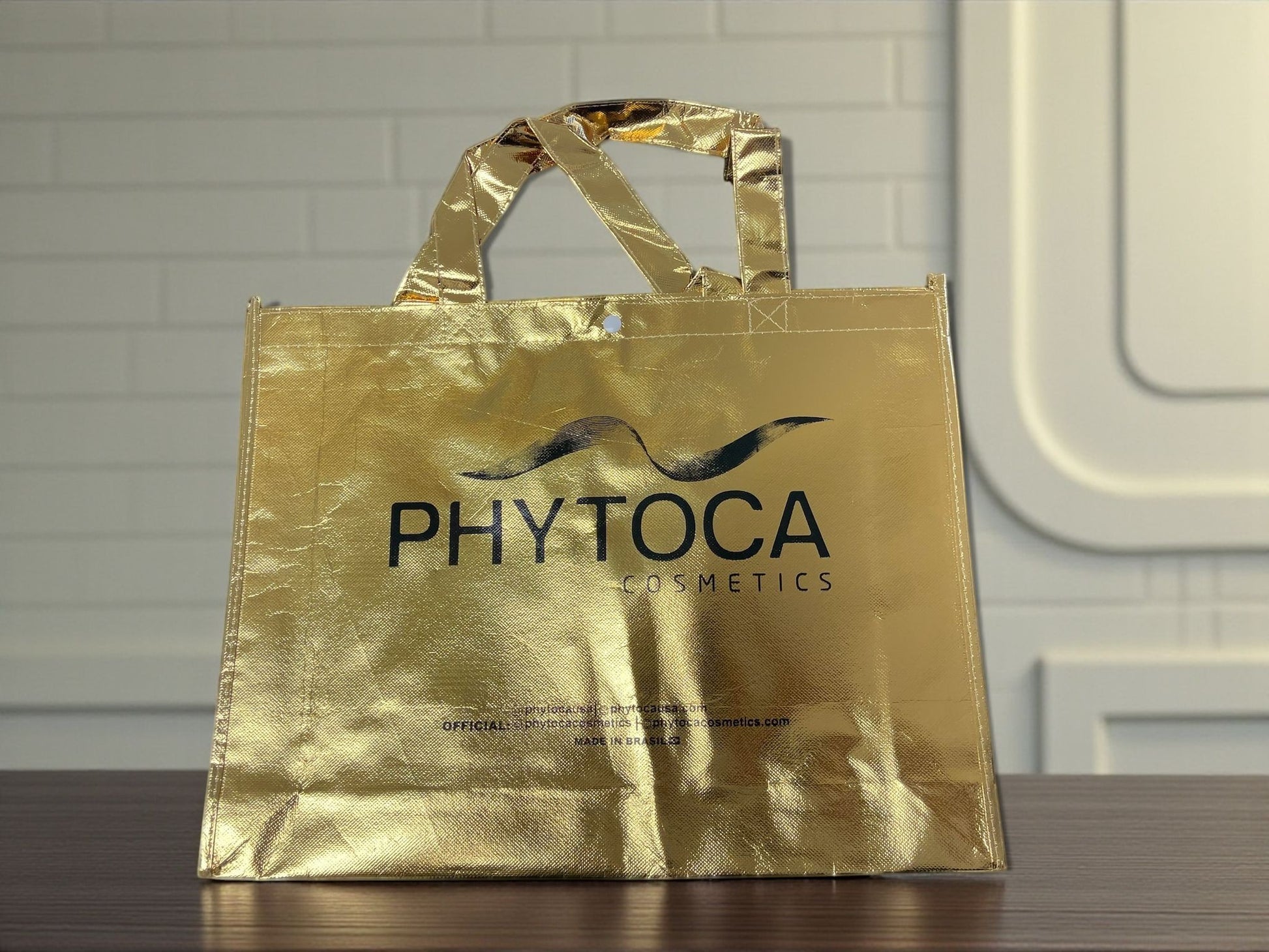 Bolsa de mano Phytoca USA de color dorado brillante con acabado metálico y logo de Phytoca Cosmetics impreso