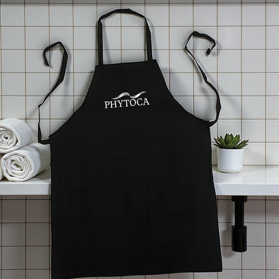 Delantal de peluquería Phytoca USA negro con bolsillos frontales y logo bordado en un salón de belleza