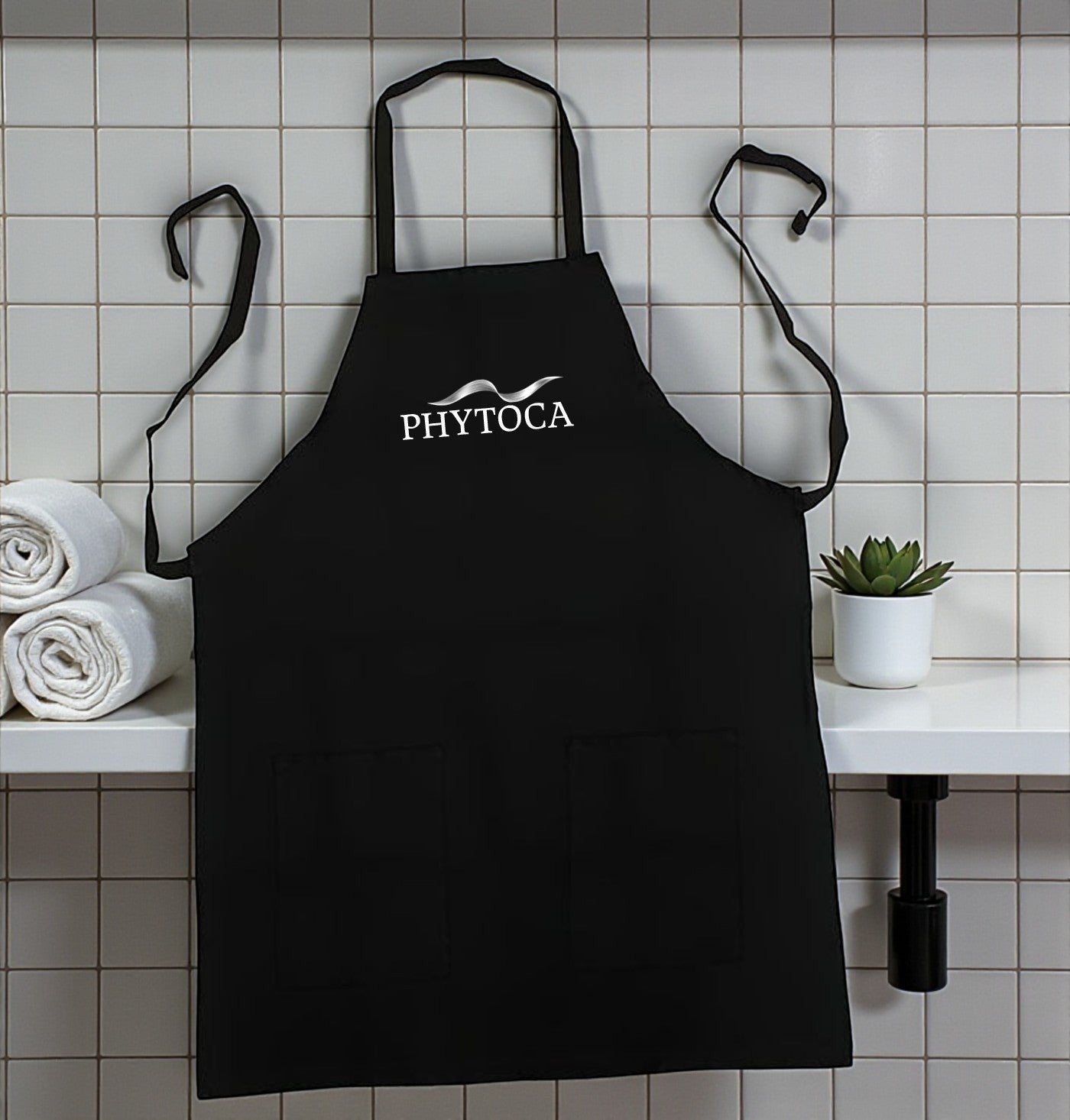 Delantal de peluquería Phytoca USA negro con bolsillos frontales y logo bordado en un salón de belleza